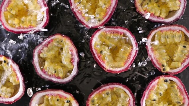 Water Splash Falling On Fresh Passion Fruit Slices In Slow Motion. Juicy Fresh Summer Fruits.