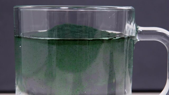 Green algae in powder spirulina dissolves in water. selective focus