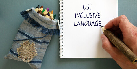 Use inclusive language symbol. Businessman writing concept words 'Use inclusive language' on white...