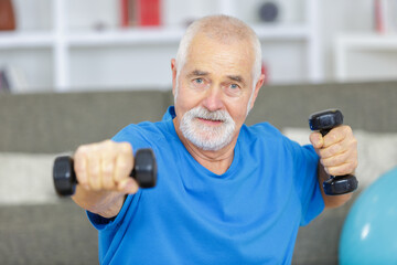 senior man lifting dumbbells at home