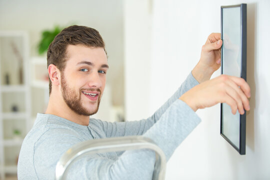 man putting picture up on the wall