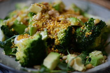 vegetarian healthy, fresh, green salad of broccoli, avocado and micro-greens with pine nuts in...