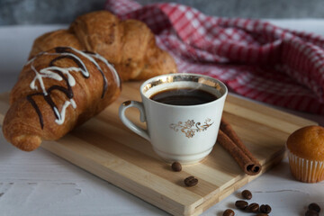 A cup of aromatic black coffee. Morning espresso or Americano coffee for breakfast in a beautiful cup. Cinnamon sticks. Wooden background.