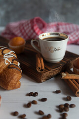 A cup of aromatic black coffee. Morning espresso or Americano coffee for breakfast in a beautiful cup. Cinnamon sticks. Wooden background.