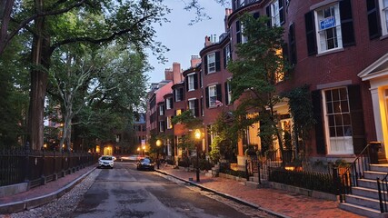 old town street at night with lamps, trees, red buildings
