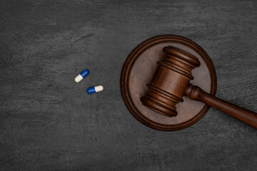 Judge gavel and two pills. Illegal use of drugs. Pharmaceutical lawsuit. Black background