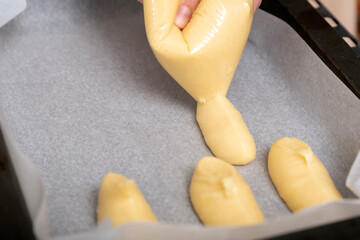 Cook squeezes the dough onto baking sheet. Cooking eclairs. Homemade pastry