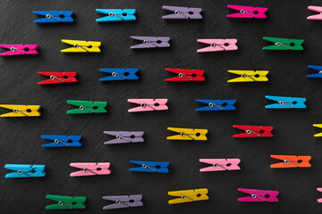 Top view on bright multi-colored clothespins. Black background. Variety of choice
