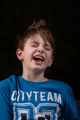 Portrait of laughing boy on black background. Happy schoolboy. Vertical frame.