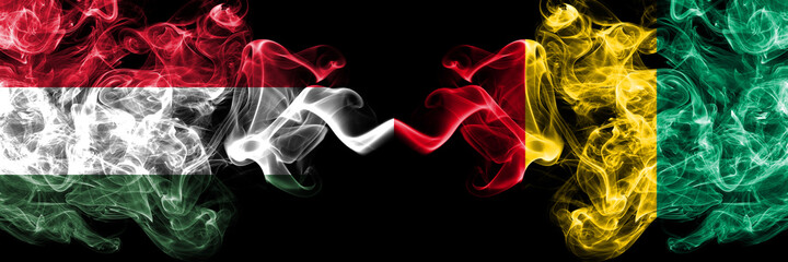 Obraz premium Hungary, Hungarian vs Guinea smoky flags side by side.