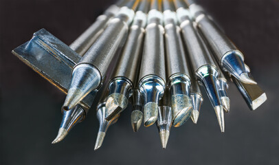 Set of soldering iron metal tips on a dark background. Various types, sizes and shapes of spiked...