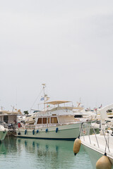 Fototapeta premium Boats parking in harbor. White motorboat at the pier. Sea yacht club. Aegean sea. Athens, Greece. White cloudy sky.