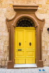 Fototapeta na wymiar Malta Mdina old wooden yellow door in a stone wall.