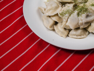 Russian dumplings on a white plate and red and white stripe  table cloth. National food.