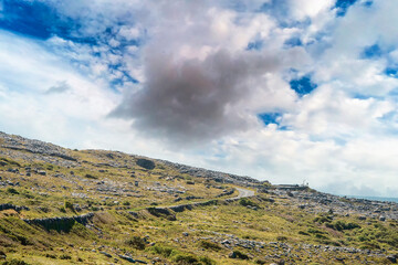 Famous rough rock landscape in Burren, county Clare, Ireland. Warm sunny day. Nobody. Stone terrain. Small asphalt road and viewing point