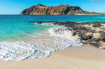 Galapagos beach landscape with strong waves, Stephens Bay with Witch Hill in background, San...