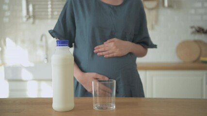 Pregnant woman concept of 4k Resolution. A woman pouring milk into a glass inside the house. - Powered by Adobe