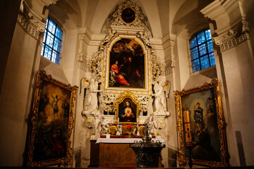 Fototapeta na wymiar Decorative interior of church St. Henry and St. Kunhuty, Chapel of St. Luke, gilded ornamented baroque altar, marble statues, wood carved frames, large paintings, Prague, Czech Republic