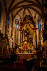 Decorative interior of church St. Henry and St. Kunhuty, gilded ornamented baroque main altar, gothic stained glass windows, marble statues, wood carved benches, Prague, Czech Republic