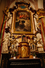 Obraz premium Decorative interior of church St. Henry and St. Kunhuty, gilded ornamented baroque altar, Infant Jesus, tall candles, marble statues, wood carved benches, Prague, Czech Republic