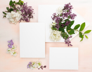 Beautiful blank wedding card with fresh lilac flowers flat lay on blush textured background