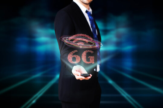 businessman presenting a hologram with message 6G on abstract blue background - Powered by Adobe
