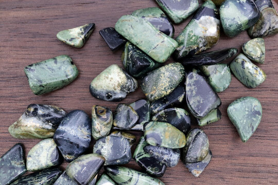 Kambaba jasper heap up jewel stones texture on brown varnished wood background