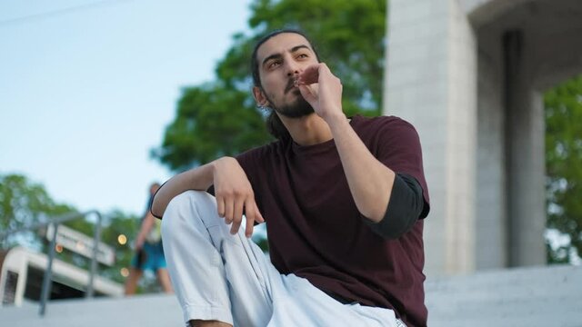 close-up portrait of handsome Arab man sitting on stairs and smoking