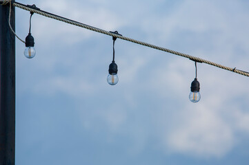 garden decoration light bulbs or outdoor area hanging by the rope tied to the black pole. behind the sky.