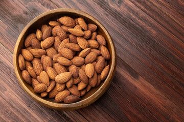 Top view of almonds in wooden bowl on the table, Flat lay, Healthy snack, Vegetarian food.