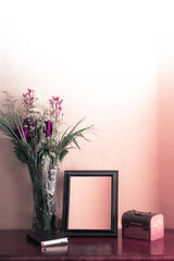 photo frame on wooden surface with a diary and a wooden jewelry box and a vase with an arrangement of withered roses in the middle of a somewhat nostalgic and sad atmosphere