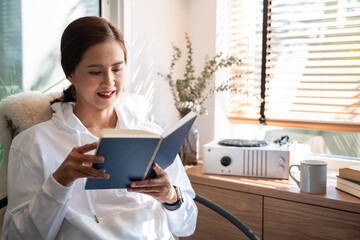 An elegant woman enjoying reading her favorite non-fiction book on the cozy chair