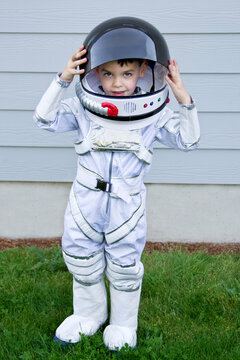 Boy child playing as an astronaut with spacesuit in yard