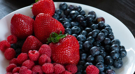 Plate of fresh juicy strawberries and blueberries, healthy summer snack