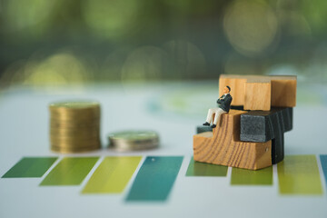 Business people sitting on wood puzzle pieces with stock of coin on graph.