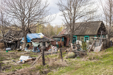 A dilapidated old residential wooden house surrounded by garbage around the house. Poverty in...