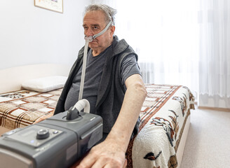 Elderly man using machine for old people who have problem with lungs.