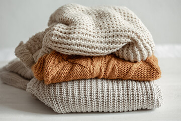 Fototapeta na wymiar A stack of warm knitted sweathers on blurred background.