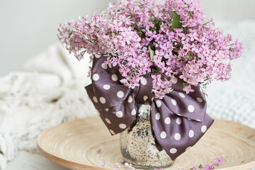 Close-up of a bouquet of lilacs in a vase with a bow.