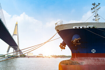 Fototapeta premium Cargo ships or break-bulk carrier. Logistics and transportation of container with Bhumibol bridge in shipyard,Thailand,with sunlight at port,logistic import export and transport industry.