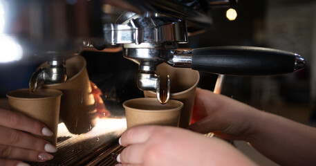 coffee maker pours hot espresso into a glass. coffee latte in a paper cup. Concept for cafe or...
