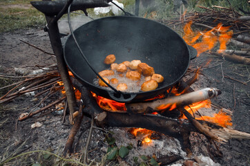 Outdoor picnic. Cooking in a hike in nature, fried potatoes over a fire in a pot.