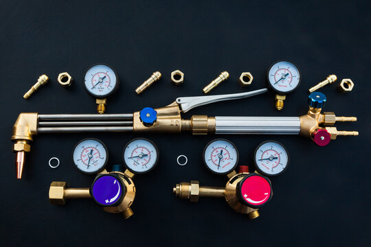 New gas cutter with nozzles, monometers and pressure regulators for oxygen and acetylene, on a black background, top view.