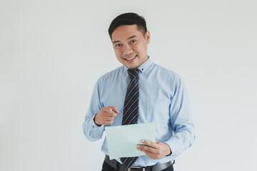 Portrait of smiling sales man wearing blue shirt and tie pointing on blank paper at camera
