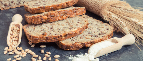 Wholegrain bread for breakfast, ingredients for baking and ears of rye or wheat grain