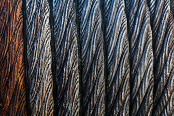A wound steel cable tightly pressed against each other, close-up. Strands of steel cable and one strand of rusty.