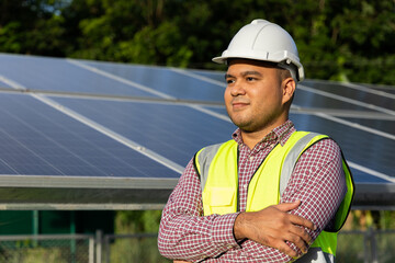 Young asian electrical engineer standing in front of Solar cell panels farm. He checking and...