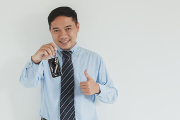 Portrait of smiling sales man wearing blue shirt and tie holding a car key and thumb up at camera with copy space
