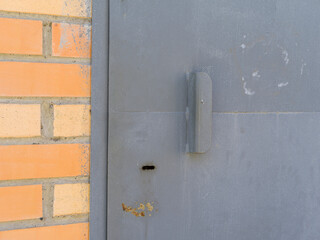Closed metal door with a door keyhole. Metal cutout. Brickwork.