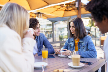 Multi-ethnic group of friends having a drink together in an outdoor bar.